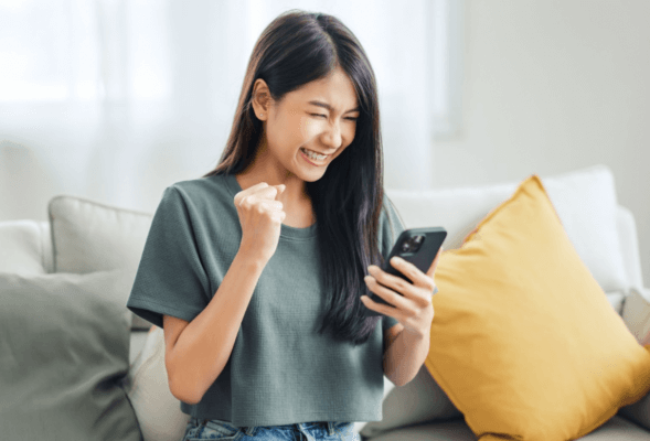 Closeup of woman on couch looking at her phone cheerful.